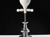 a glass candle holder with a white candle on top of it