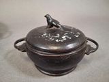 a black pot with a bird on it sitting on top of it