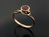 une bague en or sertie d'une pierre rouge sur un fond noir