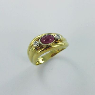 gros plan d'une bague en or avec un rubis et des diamants