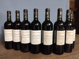 six bottles of wine are lined up on a wooden table