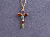 a gold cross necklace with multi colored stones on a gold chain