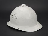 an old white helmet on a black background with a hole in it