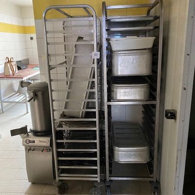 Plusieurs plateaux de nourriture sont empilés sur un chariot dans une cuisine