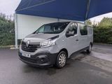 La camionnette grise est garée sous un auvent bleu sur le parking.