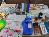 une table sur laquelle se trouvent de nombreux objets, notamment un téléphone portable, une serviette, une bouteille d'eau, une coque de téléphone portable et d'autres objets
