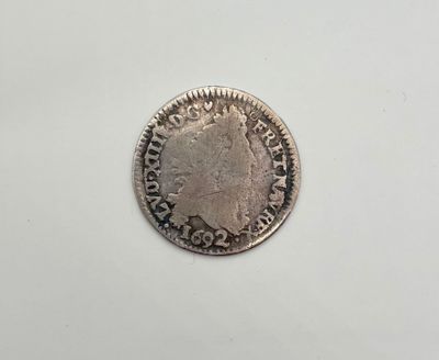 une pièce d'argent posée sur une surface blanche, sur fond blanc