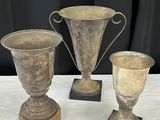 trois vases en argent posés sur une table, sur fond noir