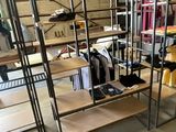 a rack of clothes in a room with a lot of shelves