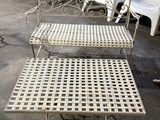 un banc en fer blanc avec deux chaises et une table