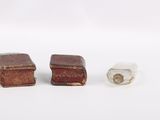 two miniature books and a glass block on a white surface