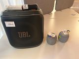 une enceinte noire posée sur une table, à côté de deux petits cailloux