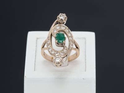 un gros plan d'une bague sertie d'un diamant et d'une émeraude posée sur une boîte blanche