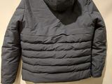 a gray jacket hanging on a hanger on a white wall