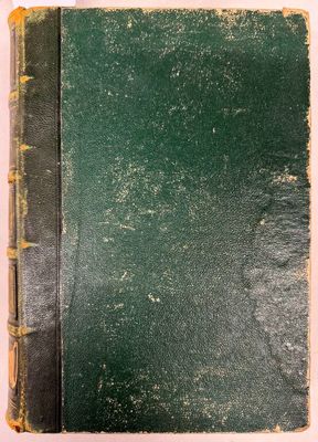 un vieux livre à la couverture verte posé sur une table