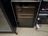 un réfrigérateur noir avec une porte vitrée et une étagère noire