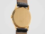 a close up of a gold watch with a black leather strap