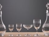 four wine glasses and a decanter on a table