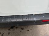 the rear end of a white truck with a red tail light