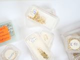 many different types of jewelry in plastic containers on a table