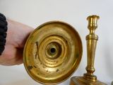 a hand holding a brass candle holder next to a gold candle