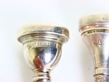 two silver candlesticks sitting next to each other on a table