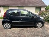 La petite voiture noire est garée devant une maison.