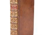 an old book with a brown cover sitting on top of a white surface