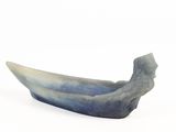 un objet en forme de bateau, bleu et blanc, posé sur une surface blanche
