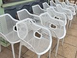 de nombreuses chaises en plastique blanc alignées sur le trottoir