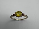 a close up of a yellow sapphire and diamond ring on a white surface