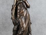 une statue en bronze représentant une femme tenant un chien, posée sur un socle en bois