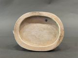 a small white bowl with a black handle on a table