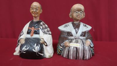 paire de figurines asiatiques posées sur un tissu rouge, sur fond rouge