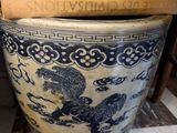 un grand vase bleu et blanc sur lequel sont empilés des livres