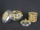 three pieces of glass with gold decoration on them on a black background