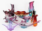 de nombreux vases en verre de différentes couleurs posés sur une surface blanche