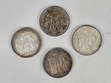 four different types of silver coins on a white surface