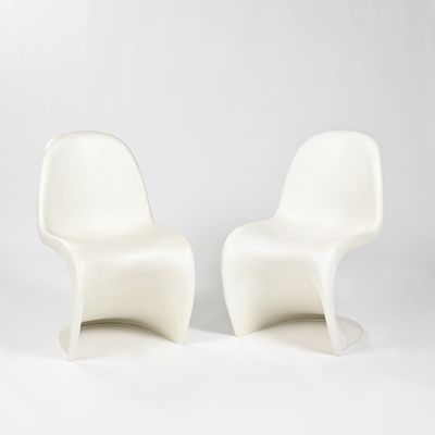 two white plastic chairs sitting next to each other on a white surface