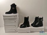 trois paires de bottes noires posées sur une pile de cartons blancs