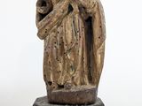 une vieille statue représentant une femme tenant un enfant dans ses bras, posée sur un piédestal