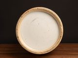 a white bowl sitting on a wooden table with a black background