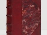 un vieux livre à la couverture rouge posé sur une table blanche