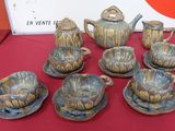 a table with a red table cloth and a set of teapots and cups and saucers
