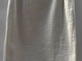 a white skirt hanging on a hanger against a wall