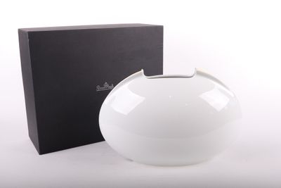 un vase blanc posé à côté d'une boîte sur une surface blanche
