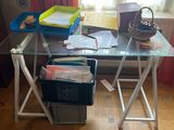 un bureau en verre sur lequel sont empilés de nombreux papiers