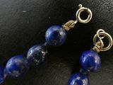 a close up of a pair of blue beads on a black surface
