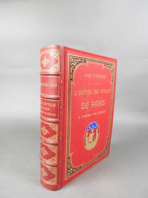 un vieux livre rouge posé sur une table à côté d'un mur blanc