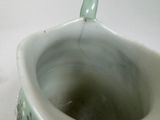 a close up of a green vase on a white table
